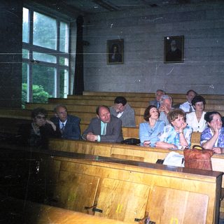 Group of people attending formal indoor gathering in wooden pews.