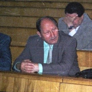 Group of people attending formal indoor gathering in wooden pews.