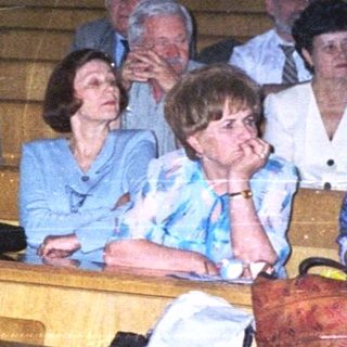 Group of people attending formal indoor gathering in wooden pews.