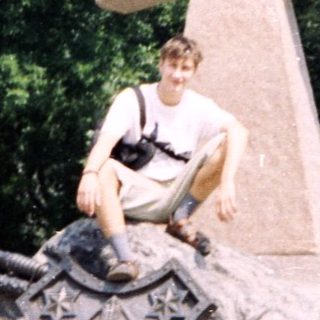 Person sitting on war memorial cross.