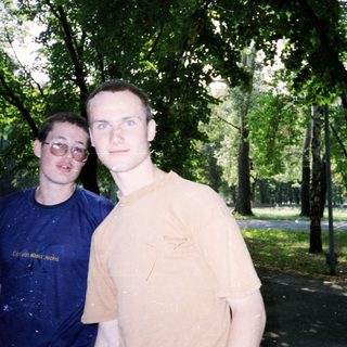 Two men posing together outdoors in a park.