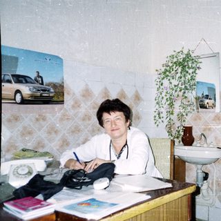 Two women sitting indoors, one writing, the other posing.