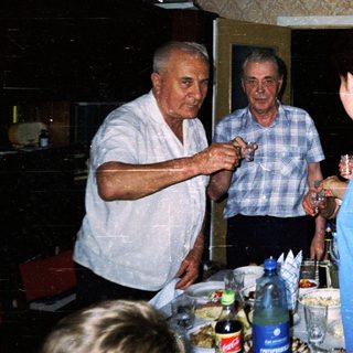 Family gathering with drinks and conversation in a home kitchen.