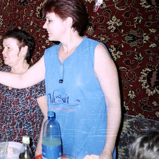 Family gathering tying ribbon on elderly woman's wrist.
