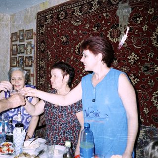 Family gathering tying ribbon on elderly woman's wrist.