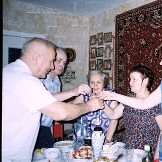 Family gathering tying ribbon on elderly woman's wrist.