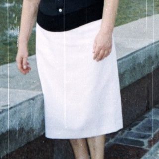 Woman posing near fountain in front of grand building.