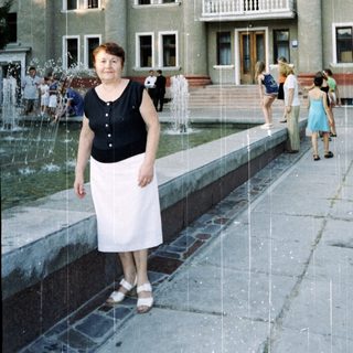 Woman posing near fountain in front of grand building.