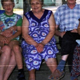 Five adults posing together outdoors near a building.