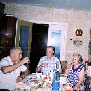 Family gathering enjoying meal and drinks indoors.