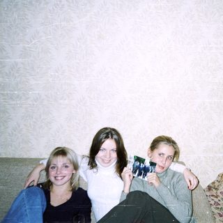Three people posing indoors with a photo.
