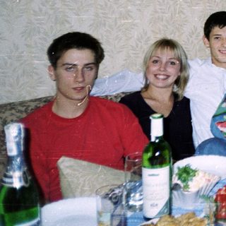 Group of six people posing at a casual indoor gathering with food and drinks.