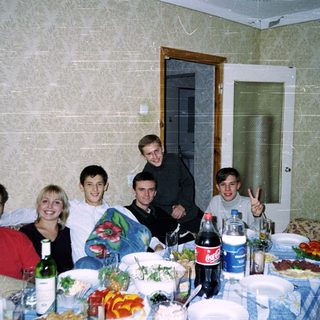 Group of six people posing at a casual indoor gathering with food and drinks.