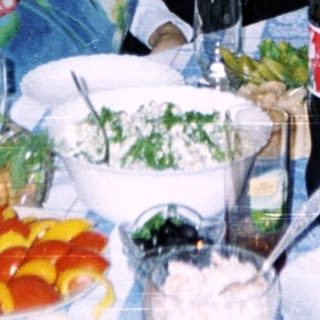 Group of six people posing at a casual indoor gathering with food and drinks.