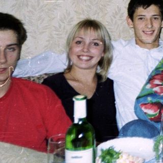 Group of six people posing at a casual indoor gathering with food and drinks.
