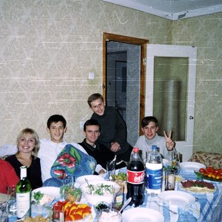 Group of six people posing at a casual indoor gathering with food and drinks.