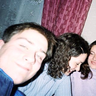 Four people smiling indoors, taking a selfie.