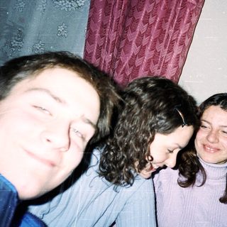 Four people smiling indoors, taking a selfie.