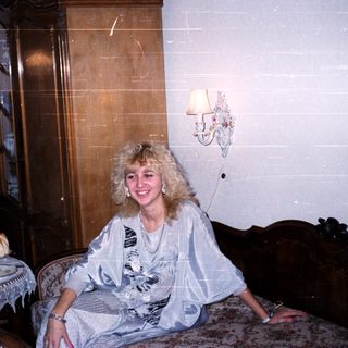 Woman sitting on vintage bed in classic interior.