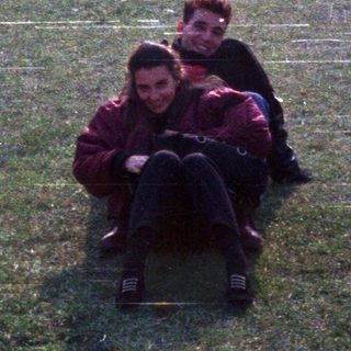 Two people sitting on grass in park.