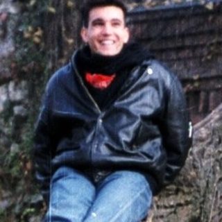 Person sitting on stone structure near historic ruins.