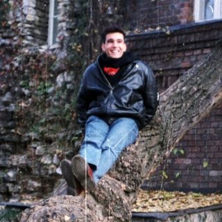 Person sitting on stone structure near historic ruins.