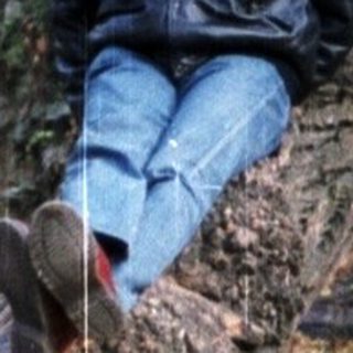 Person sitting on stone structure near historic ruins.