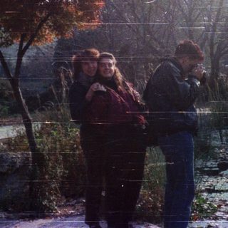 People walking in autumn park near water.