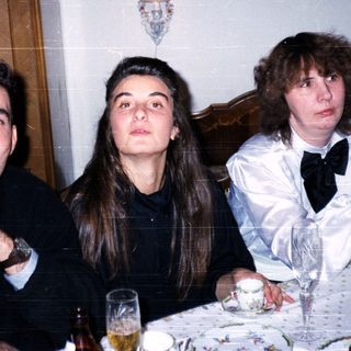 Three people dressed formally at an indoor dinner event.