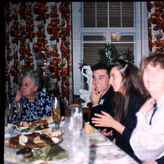 Family gathering enjoying meal indoors with vintage decor.