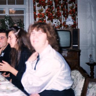 Family gathering enjoying meal indoors with vintage decor.