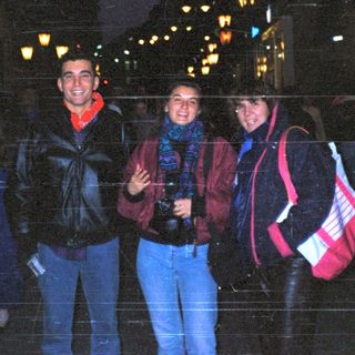 People posing together at night in city.