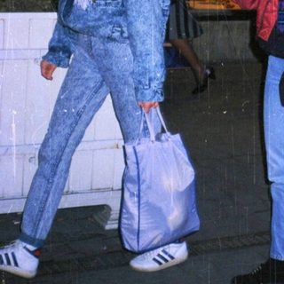 People walking outside at night near a storefront.