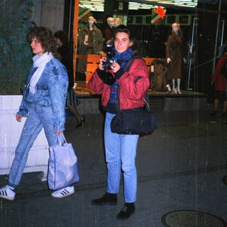 People walking outside at night near a storefront.