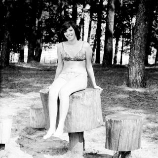 Woman sitting on tree stumps outdoors in swimwear.