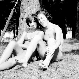 Two people sitting together under a swing in a park.