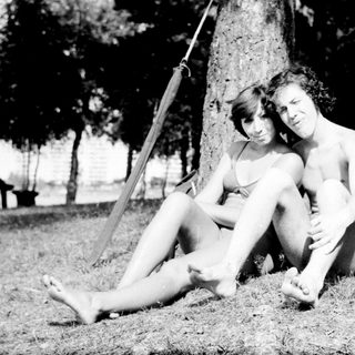 Two people sitting together under a swing in a park.