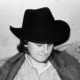 Person wearing cowboy hat writing at desk.