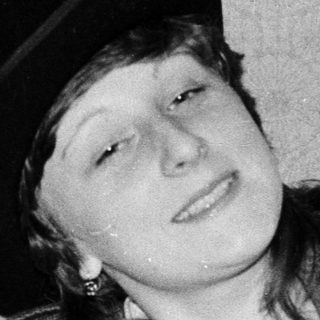 Young person reading book while wearing a fedora.