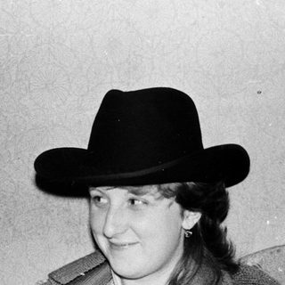 Person wearing cowboy hat reading book indoors.