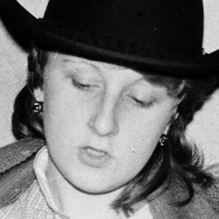 Person wearing cowboy hat reads book indoors.