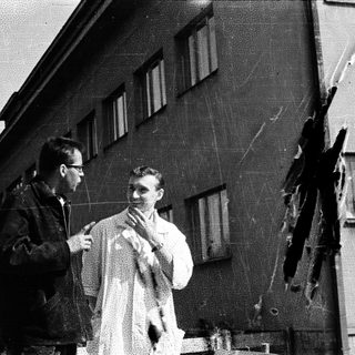 Men examine damage to building, possibly post-event.