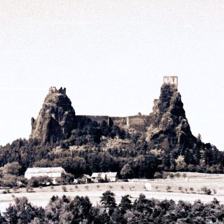 Ruins of a castle atop a hill overlooking a field.