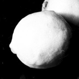 Here's a brief summary of the image: A lemon rests on a dark, reflective surface.