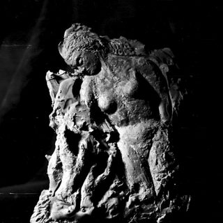 Here's a brief summary of the image: Sculpture depicting a figure in a seated, contemplative pose.