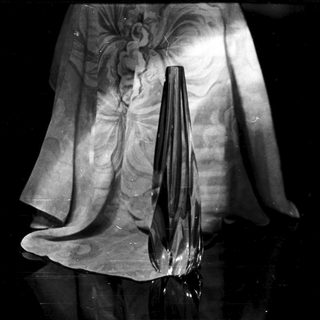 Black vase silhouette against draped fabric in monochrome.