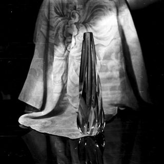 Black vase sits on a draped fabric surface.