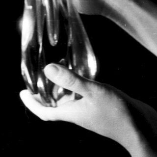 Hands hold a glass bottle in a dark space.