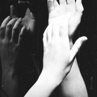 Here's a brief summary of the image: Hands are reflected in a dark, glossy surface.