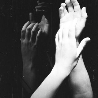 Here's a brief summary of the image: Hands are reflected in a dark, glossy surface.